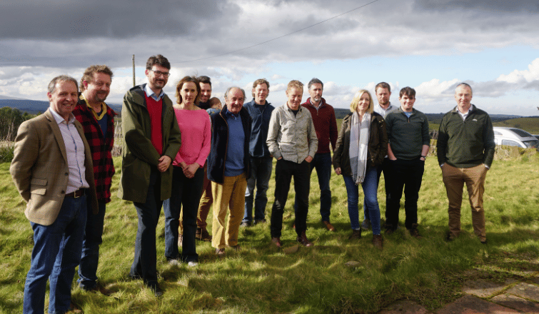 A group of adults are stood in a field