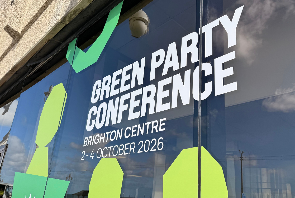 A conference centre glass window reads 'Green Party Conference 2 - 4 October 2026