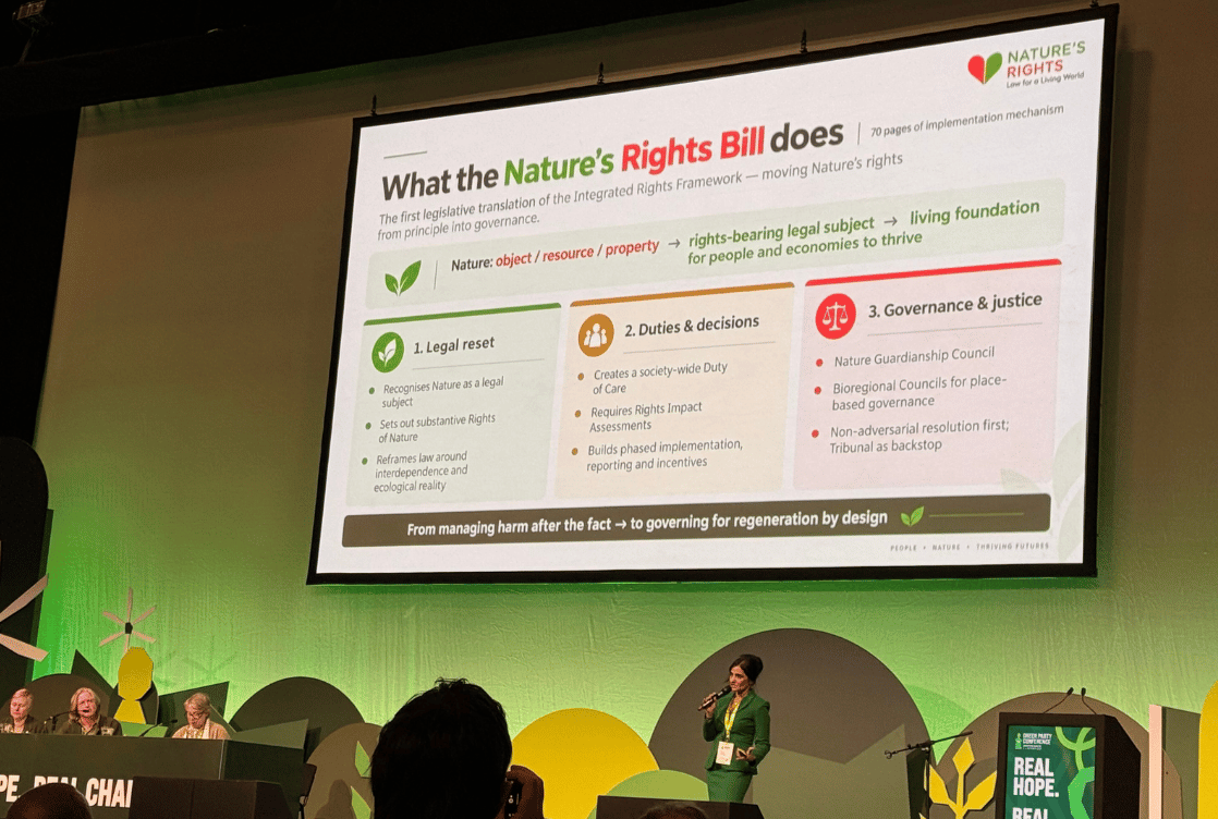 A large screen explains “What the Nature’s Rights Bill does,” above a panel and presenter in green light